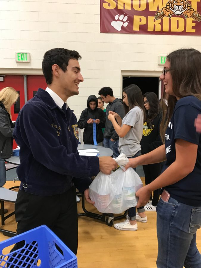 FFA officer, Walter Borba (left), collects cans for the Salvation Army from FFA member, Suzanne Cardoso. 
