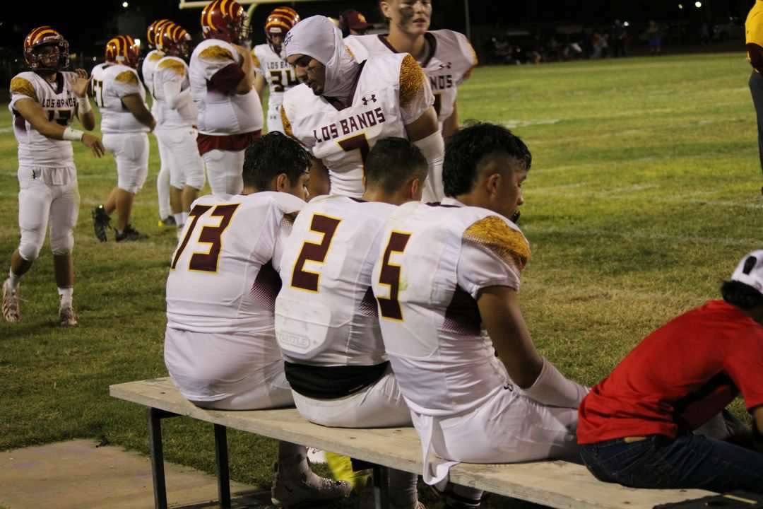Bobby Roque, David Herrera, and Yahir Zuniga sit on the bench after a scoring drive for the Tigers.