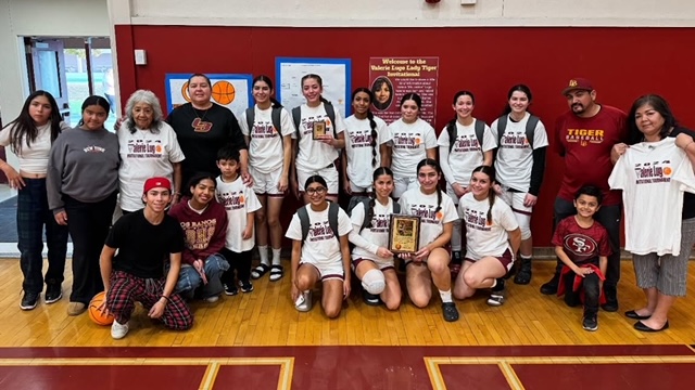 The Los Banos Girls Varsity Basketball Team pose with the Lugo family after their game.