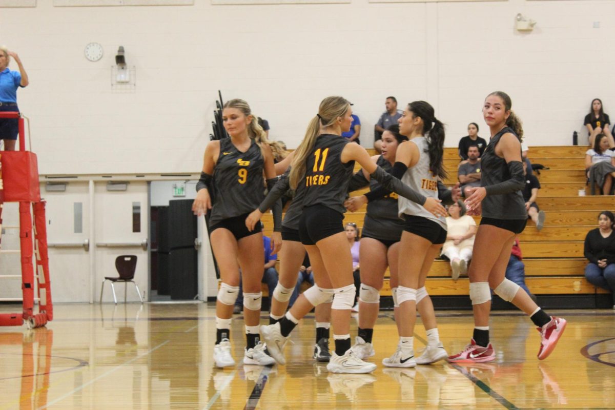 Varsity volleyball girls cheering each other up and showing sportsmanship on the court.