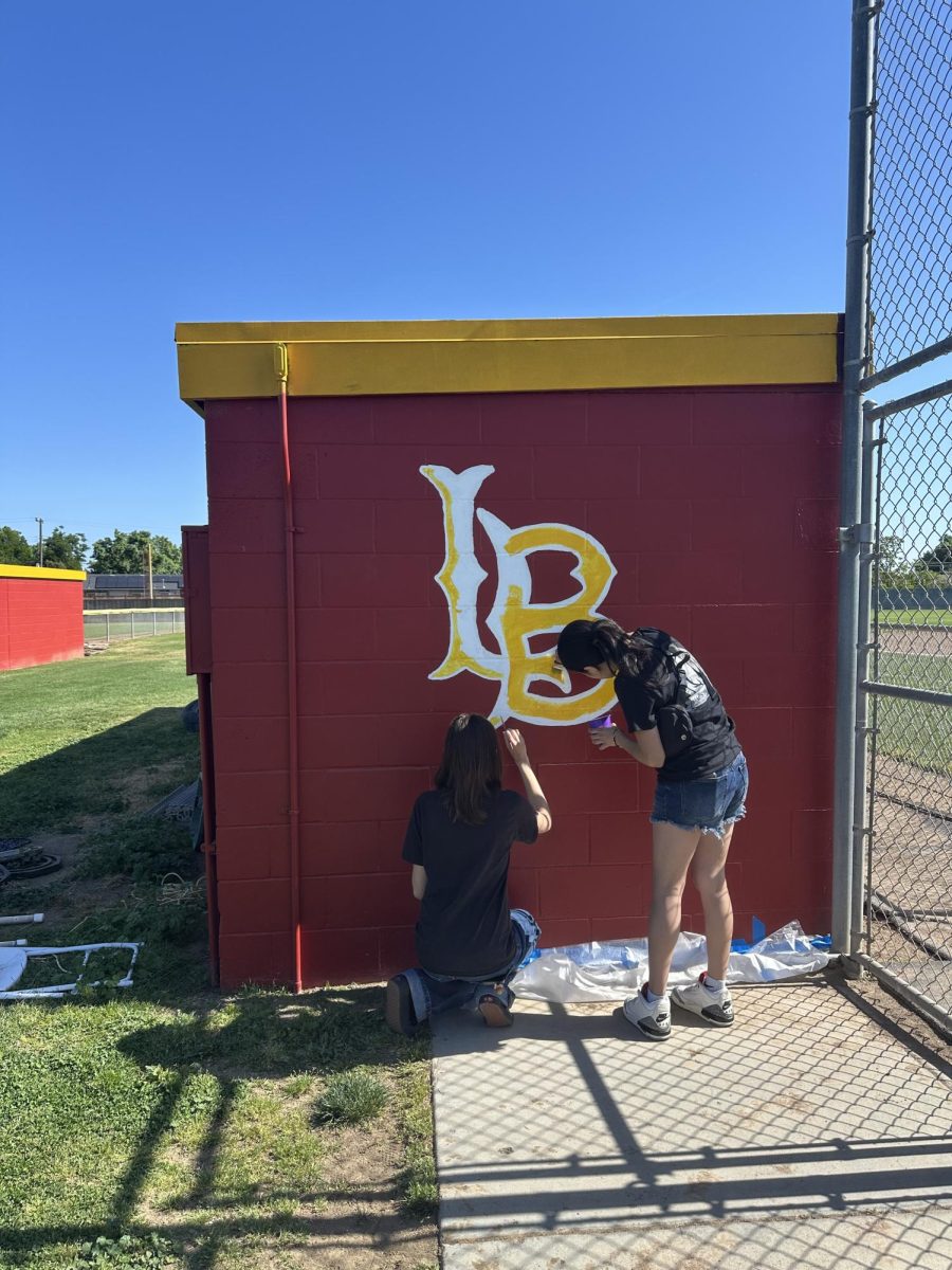 The Art Club paints logos on the baseball field area.